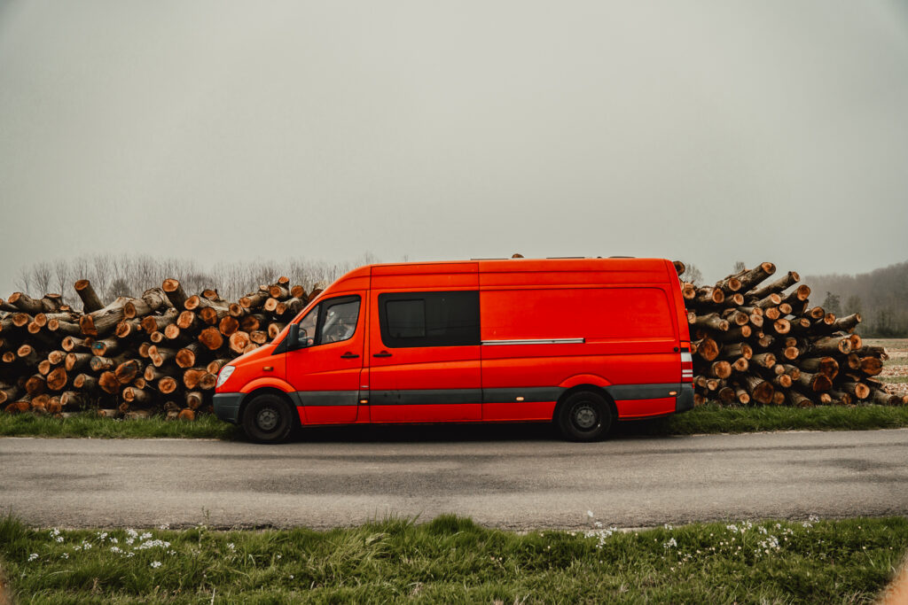 image of a red converted van against logs